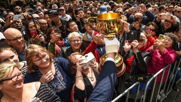 The Melbourne Cup is shown off to the crowd.