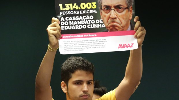 A demonstrator holds a sign that reads in Portuguese "1,314,003 people require the mandate of Eduardo Cunha be annulled" during a protest against him in Brasilia last month.