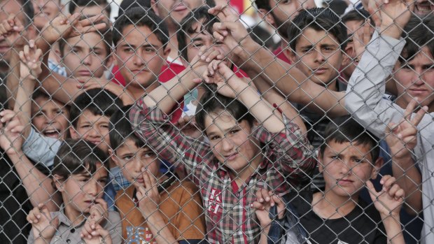 Syrians stand behind the fence at Nizip refugee camp.