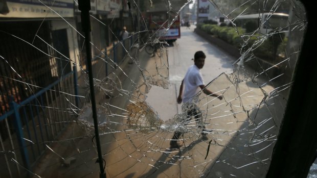 A man walks past a broken window of a bus during a protest by Dalit groups in Mumbai, India, Tuesday, Jan. 2, 2018. Protests erupted in several parts of Mumbai in January.