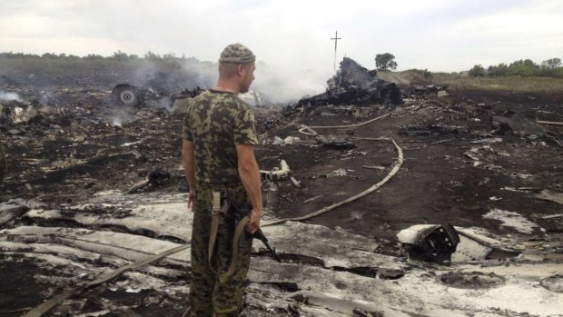 An armed pro-Russian separatist stands at the crash site of MH17 in the settlement of Grabovo, eastern Ukraine, last year. The missile strike killed 298 on board, including 39 Australians.