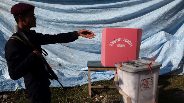 A Nepalese policeman assists voters, unseen, during the legislative elections in Balefi Nepal on Sunday.