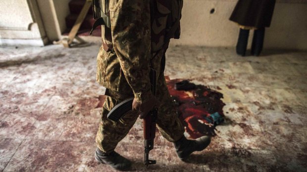 A soldier walks past blood on the auditorium floor at the Army Public School, which was attacked by Taliban gunmen.