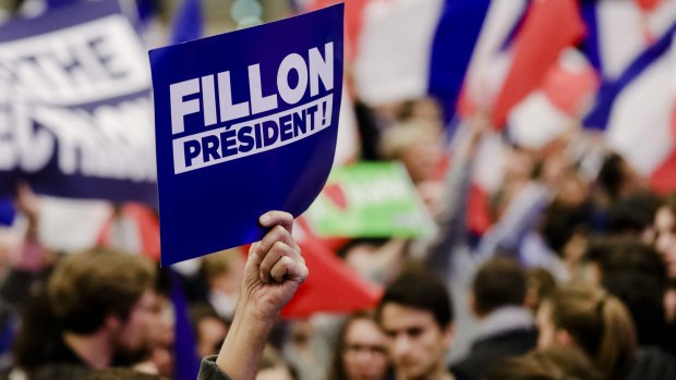 A supporter holds up a sign during an election campaign meeting for Francois Fillon in Paris.
