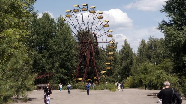 Tourists explore the abandoned amusement park and ferris wheel in Pripyat.
