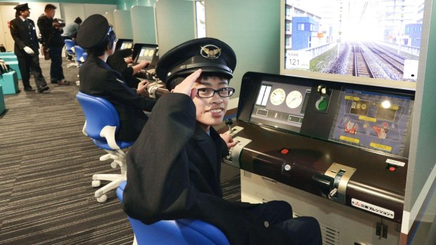 A boy takes a turn on a driving simulator, used by professional train drivers for training, at the Kyoto Railway Museum in Kyoto.