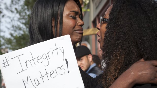 NAACP member Kitara McClure (left) cries as she hugs Angela Jones (right) during a protest against Rachel Dolezal in front of the NAACP headquarters in Spokane, Washington.