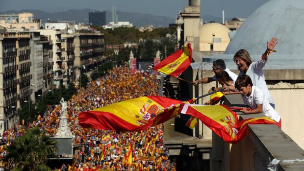 People on a rooftop wave Spanish flags during a march in downtown Barcelona, Spain, to protest the Catalan government's push for secession from the rest of Spain, on Sunday.