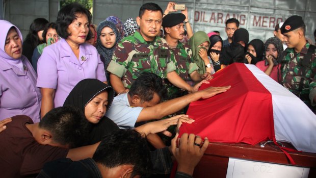 Relatives of Sergeant Ando Dandi, one of the victims of a military plane that crashed onto a residential area on Tuesday, pray at his coffin at Suwondo Airbase in Medan.