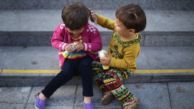 Young migrant children play as they wait to board a train to Austria at Keleti station in Budapest on Monday.