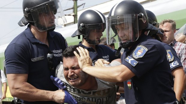 A migrant is detained after the train he was travelling on from Budapest arrived in Bicske, Hungary.