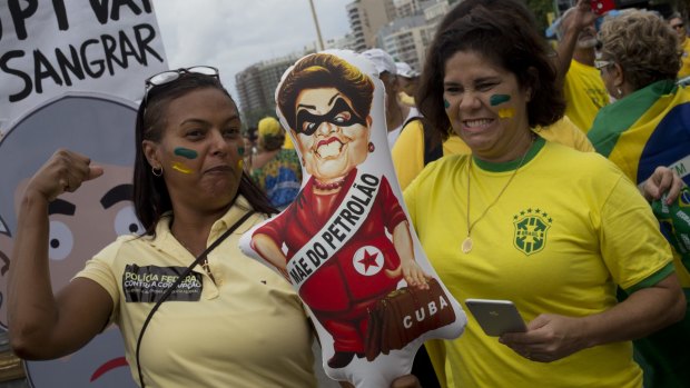 Demonstrators pretend to hit a doll depicting President Dilma Rousseff as a Cuba-sympathising oil revenue thief.