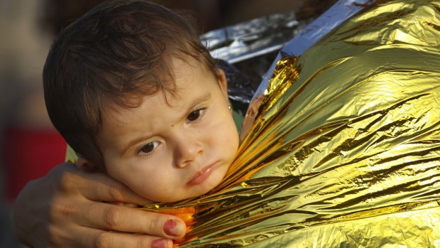 A Syrian refugee child is covered by thermal blanket in Kos following a rescue mission.
