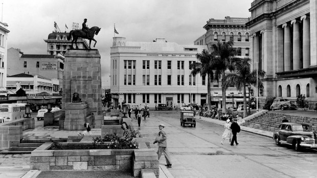 A historic photo of King George square, Brisbane, where an equestrian statue of the late King George V faces the entrance to the city hall. The memorial is surrounded with garden plots and fountains.