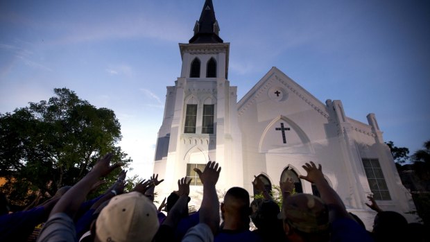 The men of Omega Psi Phi Fraternity lead a crowd of people in prayer outside the Emanuel AME Church on Friday.