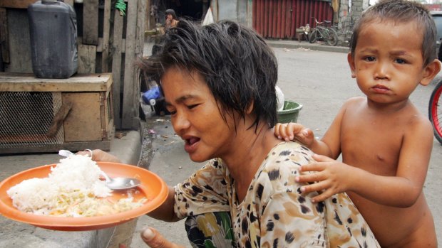 A homeless woman prepares to feed her son on the side of the street in Manila in 2008.