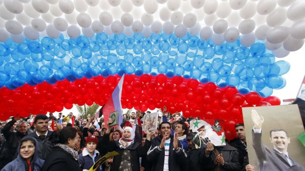 Pro-Syrian government protesters gather under a large Russian flag made with balloons as they cheer a convoy believed to be transporting Russian Foreign Minister Sergey Lavrov in Damascus, Syria, in 2012.