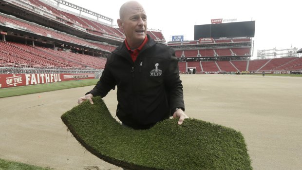 NFL field director Ed Mangan holds up a piece of turf as he speaks about the field preparation for Super Bowl 50 at Levi's Stadium.