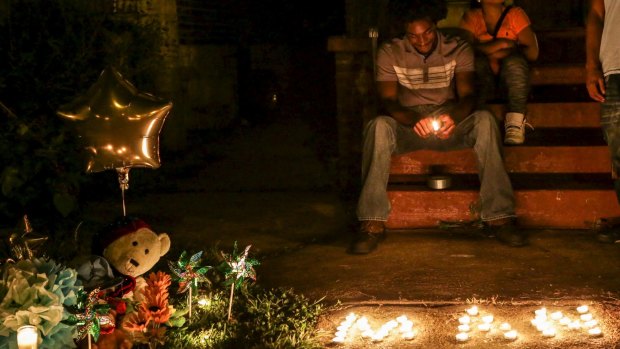 Chris Ball-Bey, the brother of Mansur Ball-Bey, sits by his brother's memorial after a candlelight vigil on Walton Ave in St Louis.