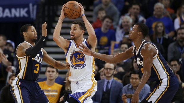 Golden State Warriors' Stephen Curry looks to get past Utah Jazz's Trey Burke (3) and Rodney Hood.