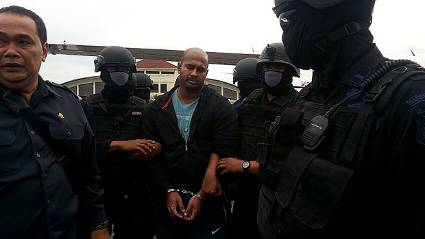 Myuran Sukumaran is surrounded by masked security personnel upon arriving at Cilacap airport.