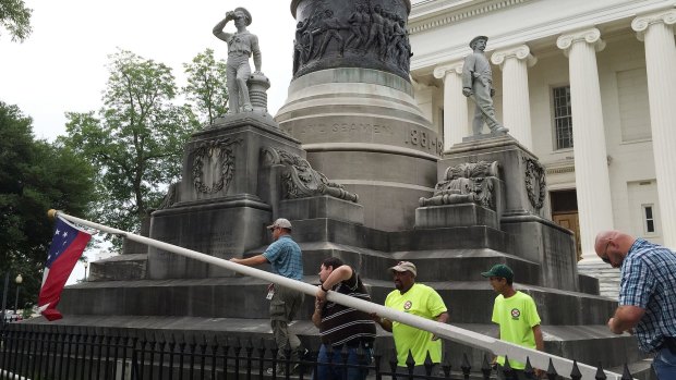State workers on Wednesday take down a Confederate national flag in the grounds of Alabama's state Capitol.