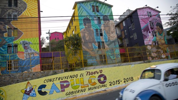 A taxi drives past the Cuauhtemoc Housing Unit and a municipal sign with a message that reads in Spanish; "Building the new Acapulco". The upsurge in killings has made Acapulco one of Mexico'­s most violent places.