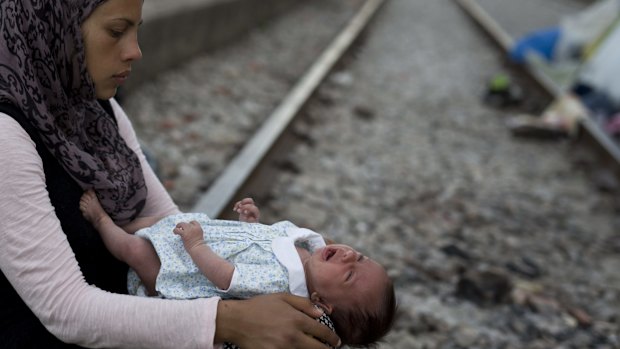 Rajad, 19, from Syria, holds her 42-day-old baby girl Yasmin at a makeshift refugee camp at the northern Greek border point of Idomeni on Friday. 