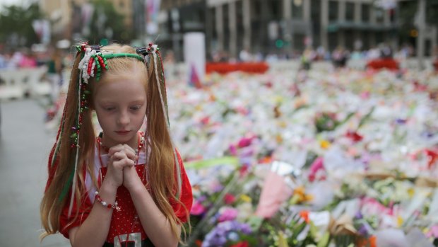 One year anniversary: A young girl dressed in Christmas attire walks around the thousands of floral tributes left in Martin Place a few days after the siege.
