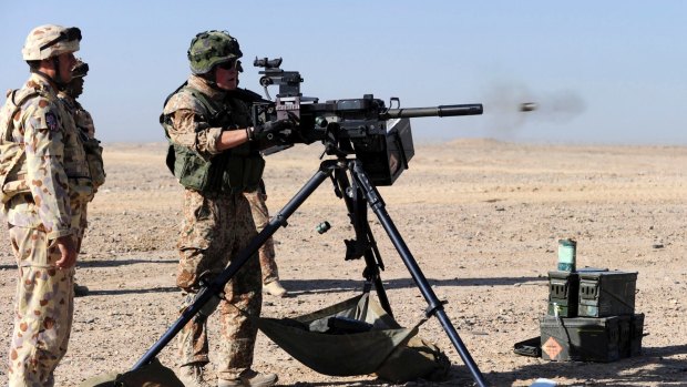 An Australian Field Battery officer supervises a Danish soldier firing the Heckler and Koch Grenade machine gun during practice in Afghanistan.