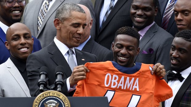 President Barack Obama holds up a Denver Broncos jersey as he welcomes the Super Bowl Champions to the White House on Monday. He is likely to start campaigning for Hillary Clinton this week.