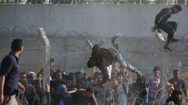 Desperate Syrian refugees cross into Turkey over and through a hole on the border fence.