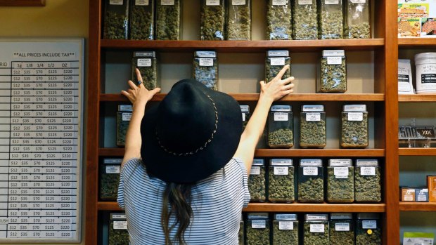 A shop assistant arranges jars of marijuana on shelves at a retail and medical cannabis dispensary in Boulder, Colorado.