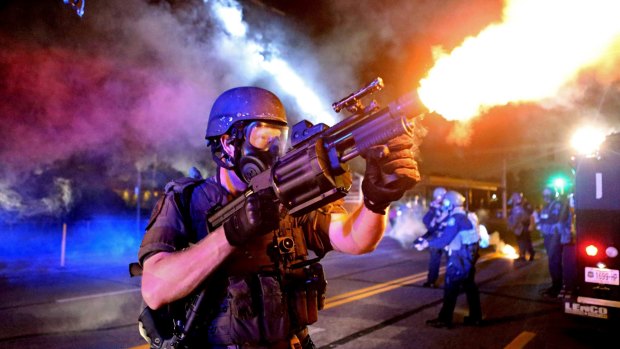 A member of the St. Louis County Police tactical team fires tear gas into a crowd of The St. Louis Post-Dispatch received the Pulitzer prize in photography for its coverage of the Ferguson, Missouri riots.