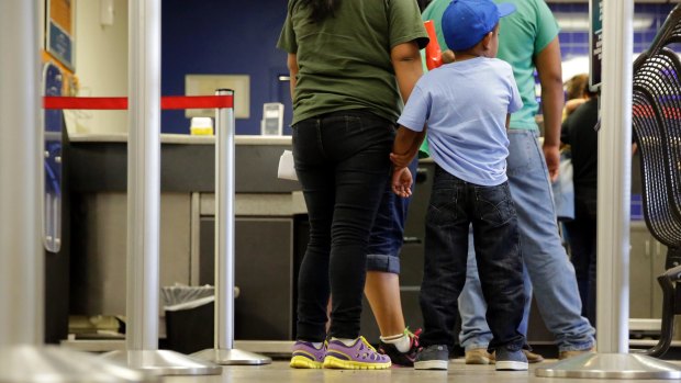 Asylum seekers from El Salvador stand in line at a bus station after they were released from a family detention centre in San Antonio, Texas. 