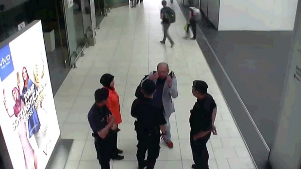 Kim Jong-nam, in grey, gestures towards his face while talking to airport security shortly before his death.