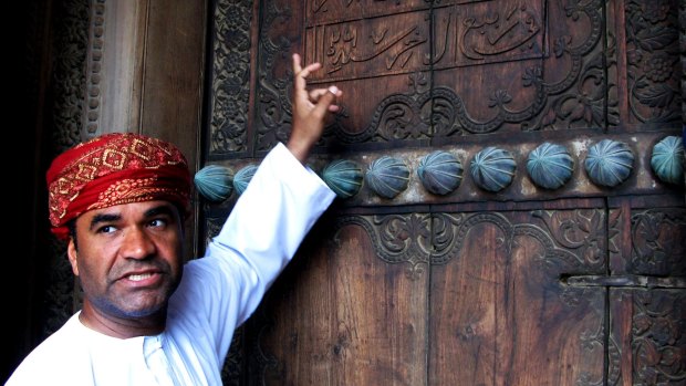 An Omani tour guide explains the meaning of words on the gate of Al Hazm Fort.