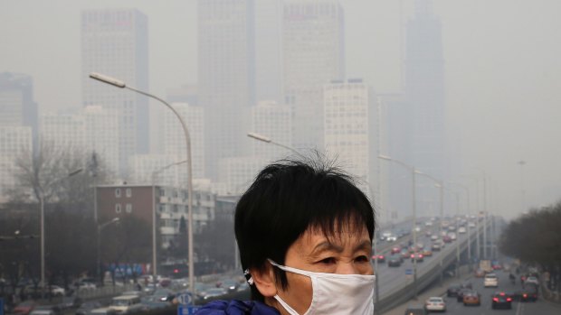 A woman wearing a mask for protection against pollution walks on a pedestrian overhead bridge in Beijing. 