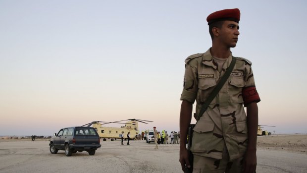An Egyptian soldier stands guard as emergency workers unload bodies of victims from the crash of a Russian aircraft over the Sinai peninsula from a police helicopter to ambulances at Kabrit military airport, some 20 miles north of Suez in Egypt on Saturday. 