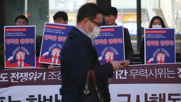 A man walks past a group of South Koreans protesting against US President Donald Trump near the US embassy in Seoul on Wednesday.