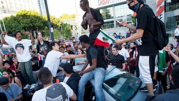 Protesters against Republican presidential candidate Donald Trump climb on a car outside campaign rally in San Jose, California. 