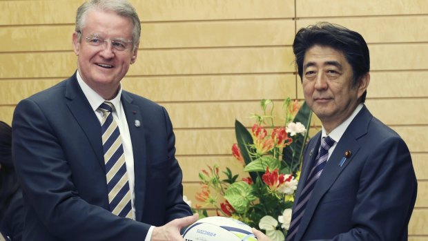World Rugby chairman Bernard Lapasset presents a rugby ball to Japanese Prime Minister Shinzo Abe during a meeting in Tokyo on Monday.