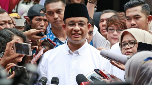 Anies Baswedan, centre, is mobbed by the press after casting his vote.