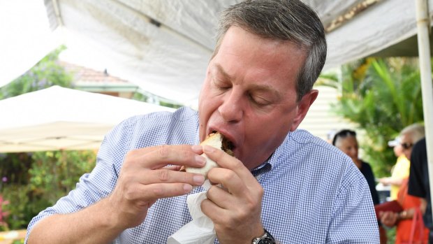Opposition Leader Tim Nicholls eats a democracy sausage at St John's Church in Hendra in his electorate of Clayfield.