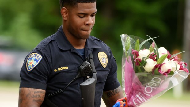 Baton Rouge Police Department Officer Markell Morris holds a bouquet of flowers and a Superman action figure that a citizen left at the Our Lady of the Lake Hospital.