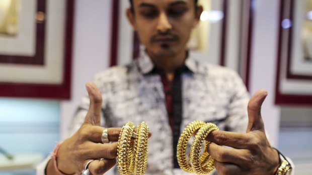 A sales assistant displays gold bangles at the store.