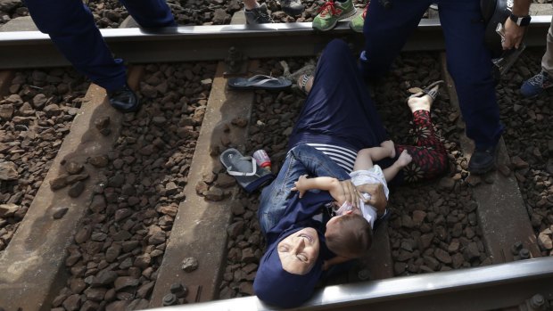 A woman lies on the track with a baby as she is detained in the Hungarian town of Bicske.