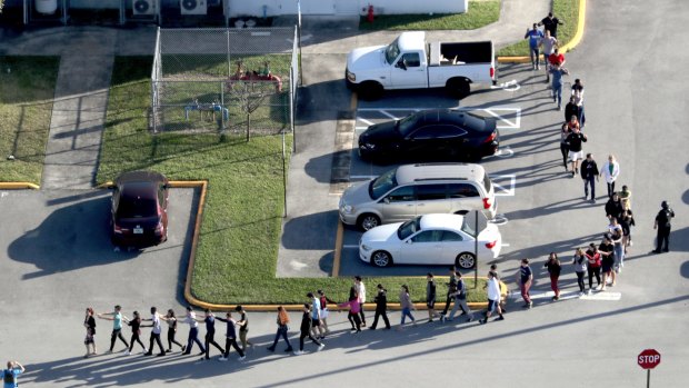 Students are evacuated by police from Marjory Stoneman Douglas High School in Parkland, Florida after the shootings.