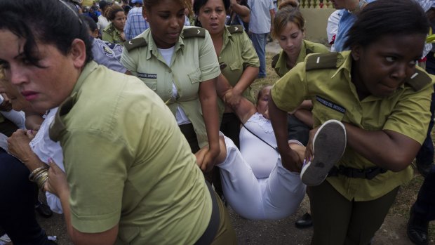 A member of the "Ladies in White," a group founded by the partners and relatives of jailed dissidents that regularly protests against the Cuban government, is carried away by police officers hours before US President Barack Obama began his visit to Havana.