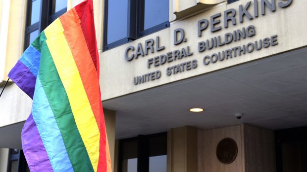 A protester waives a rainbow flag outside the Carl D. Perkins Federal Building in Ashland, Kentucky before Kim Davis' appearance last week.
